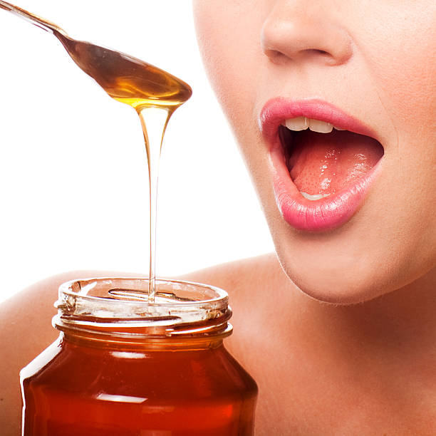 closeup of female mouth and spoon with honey