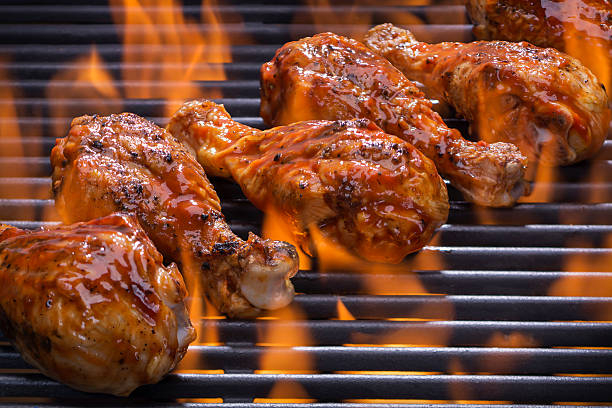 Chicken legs grilling over flames on a barbecue