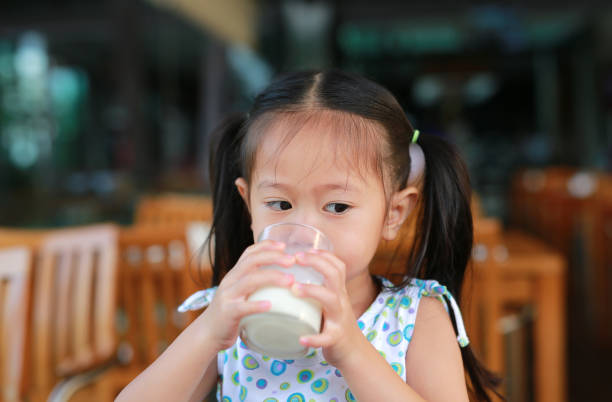 Asian little girl is drinking a milk from glass.