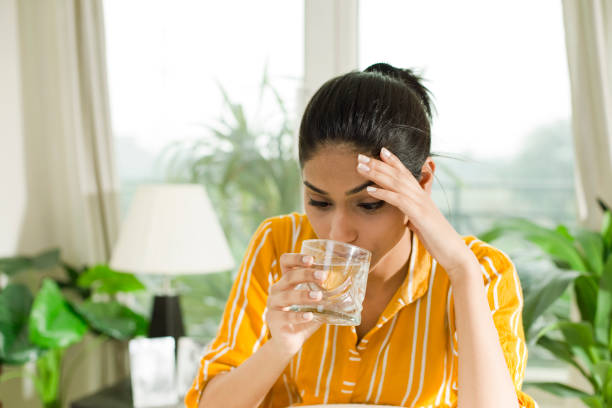 Woman with headache drinking a glass of water